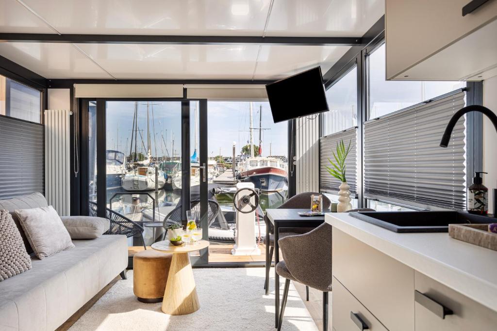 a kitchen and living room with a view of a marina at Cosy tiny houseboats near beach and restaurants in Zeewolde