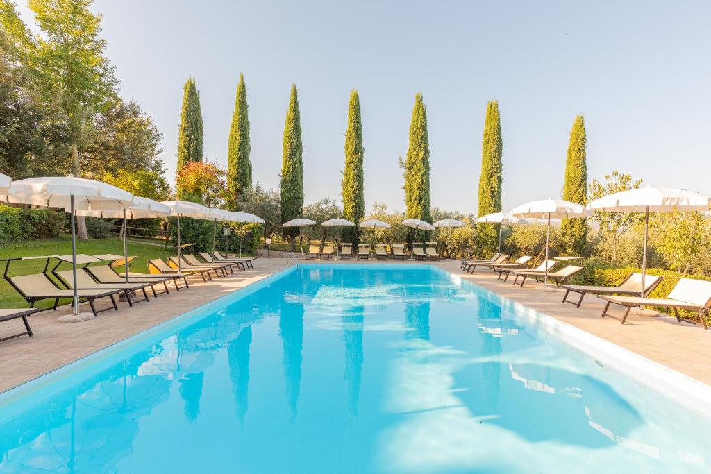 a large swimming pool with chairs and umbrellas at Appartamento Moraiolo in Montepulciano
