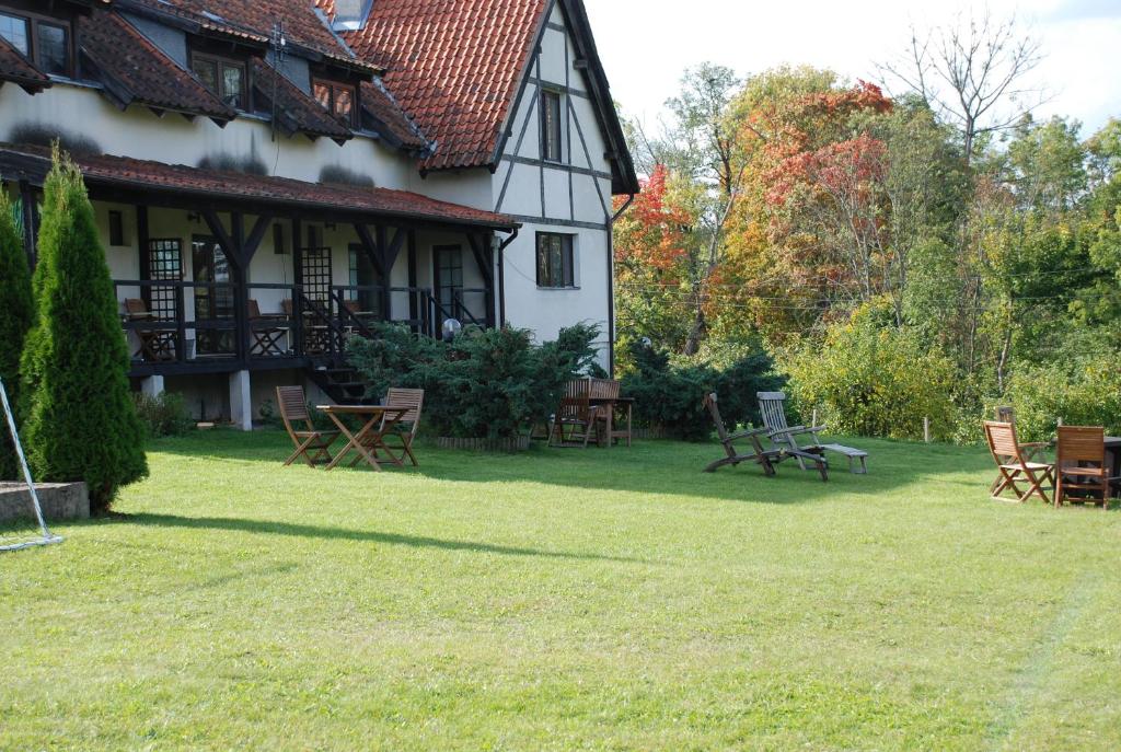 a house with picnic tables and chairs in the yard at Natura Apartamenty in Swaderki