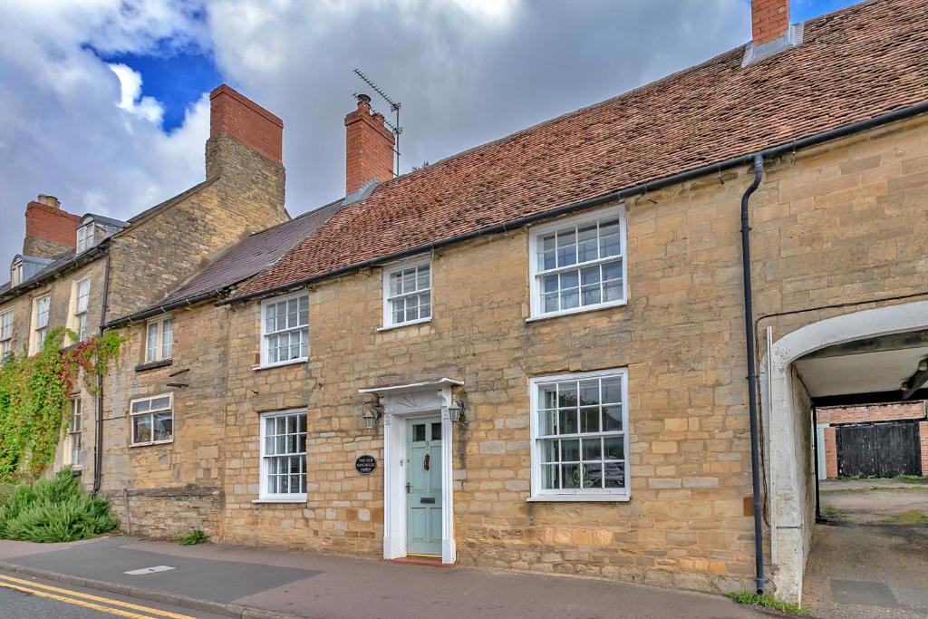 an old brick building with a white door at Finest Retreats - The Old Coach House in Stony Stratford