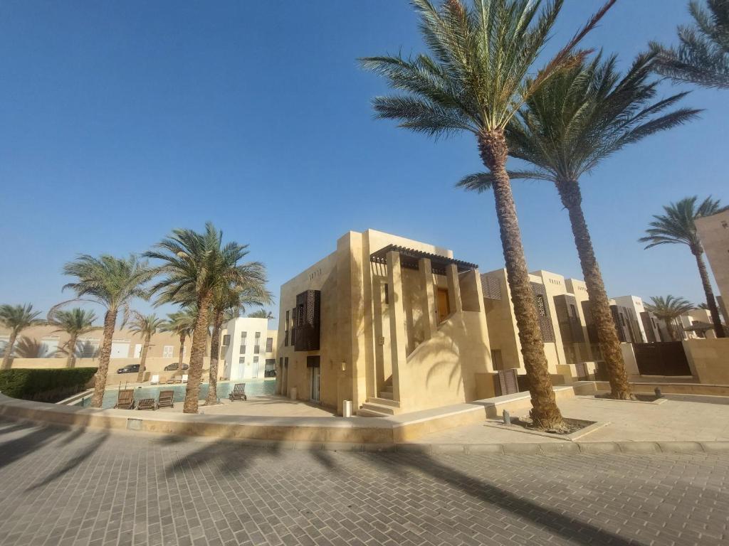 a building with palm trees in front of a street at Nayah Stays, Ground terraces Studio in Hurghada