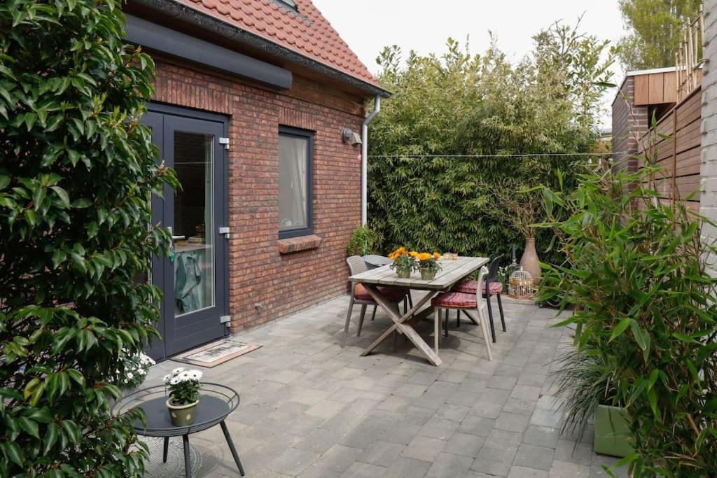 Un patio con mesa y sillas y un edificio. en Vrijvakantiehuis Duinweg 2b, en Oostkapelle