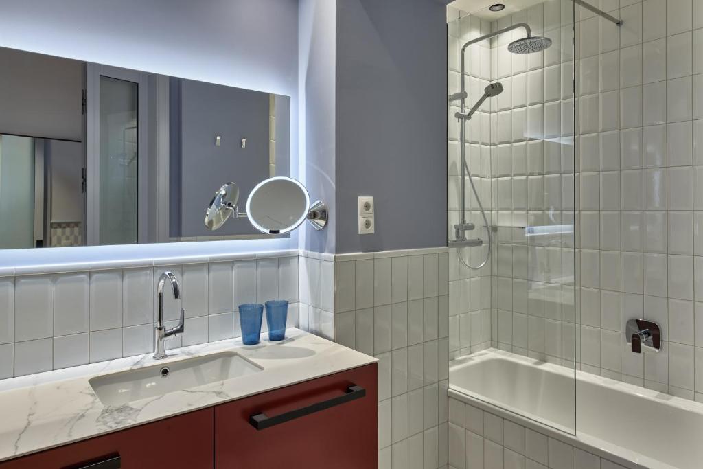 a bathroom with a sink and a shower and a tub at Falkensteiner Boutique Hotel Prague in Prague