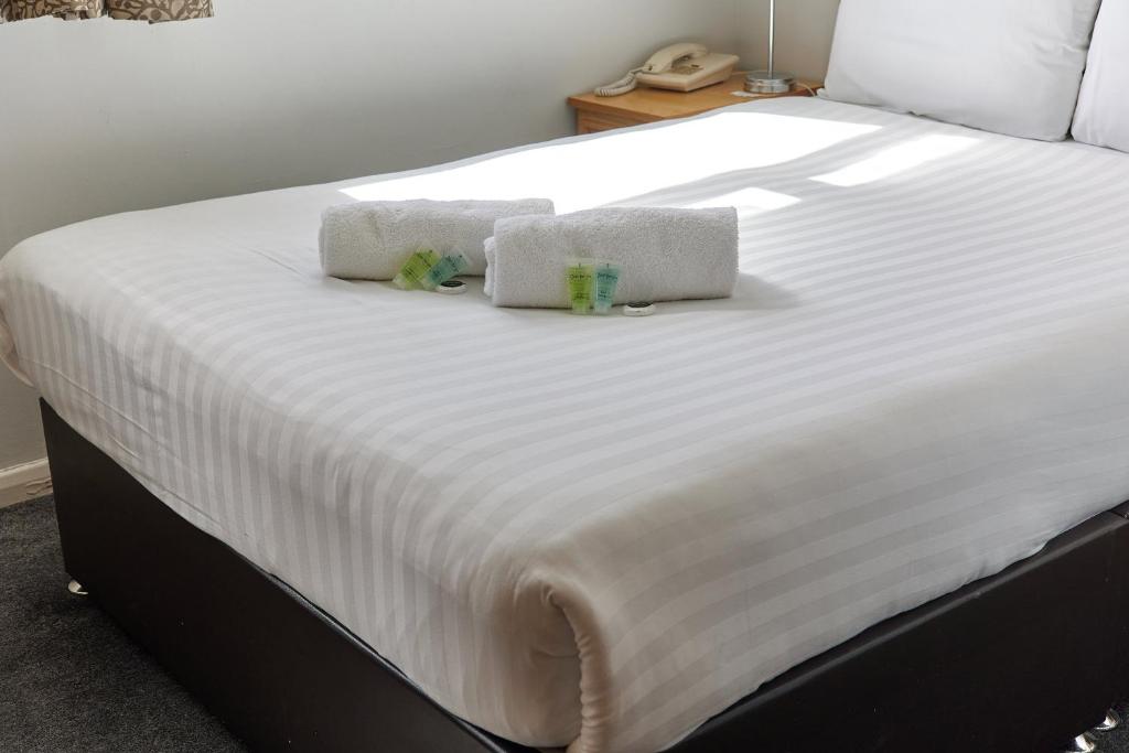 a large white bed with two towels on it at Properties Unique Dene Rooms - Double Room in Newcastle upon Tyne