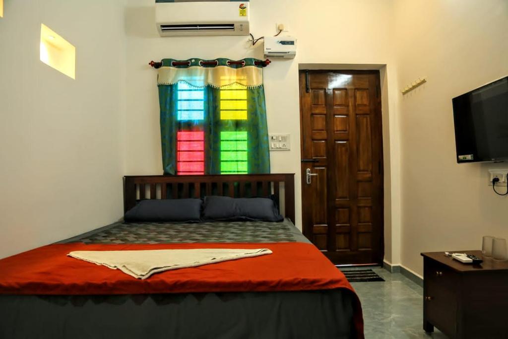 a bedroom with a bed with a colorful window at Tree shadow Guest house nearby Beach in Mahabalipuram