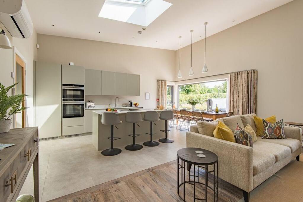 a large living room with a couch and a kitchen at The Old Cherry Barn - Luxury barn conversion in Faversham