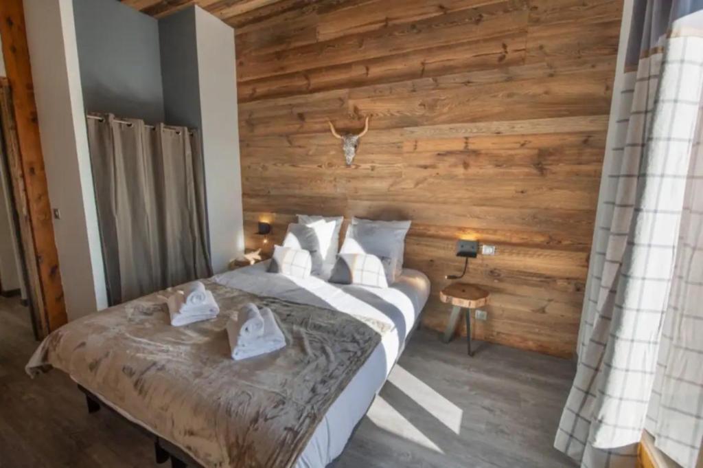 a bedroom with a large bed with a wooden wall at Chalet 2 sur la route du tour in LʼHuez
