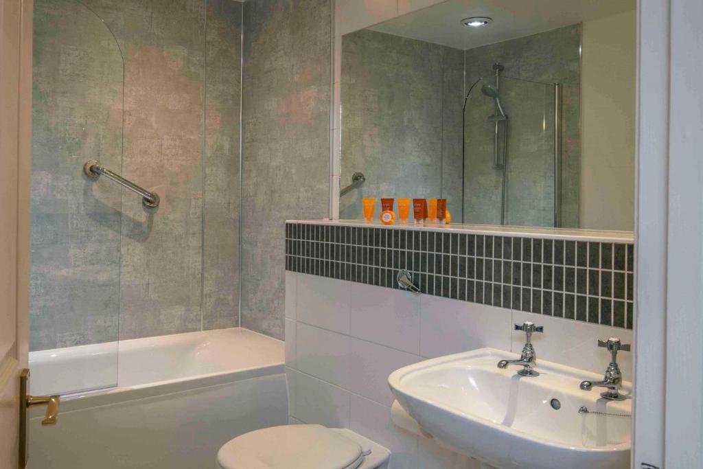 a bathroom with a sink and a toilet and a tub at Old Hunstanton Le Strange Arms Hotel in Hunstanton