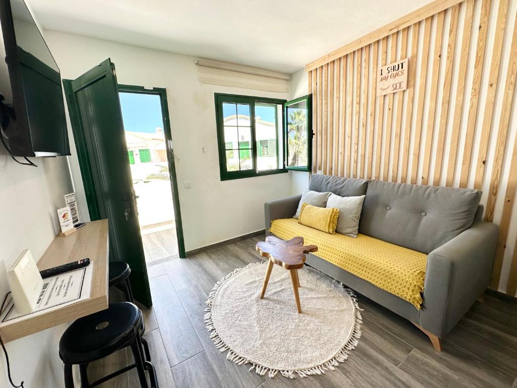 un salon avec un canapé et une table dans l'établissement Kiwi Smoothie - En la playa, doble terraza, cocina completa, dos camas y Wifi, à El Cotillo