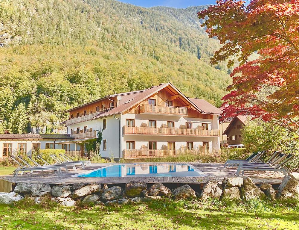 a large house with a swimming pool in front of it at Seehotel am Hallstättersee in Obertraun