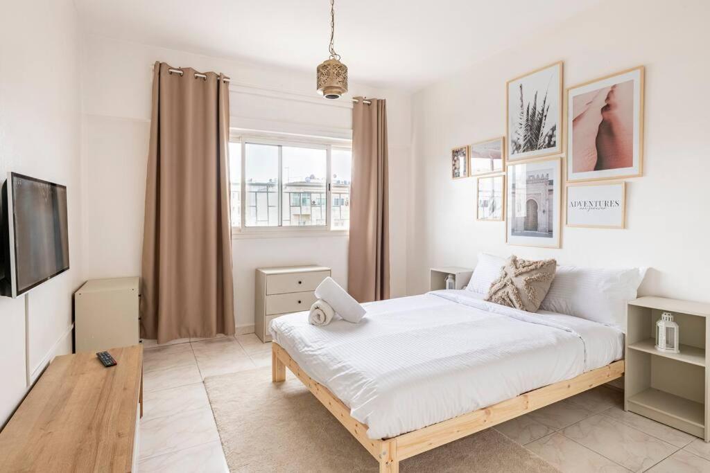 ein weißes Schlafzimmer mit einem Bett und einem TV in der Unterkunft Charmant & Spacieux 2Chambres-5 min Gare Agdal in Rabat