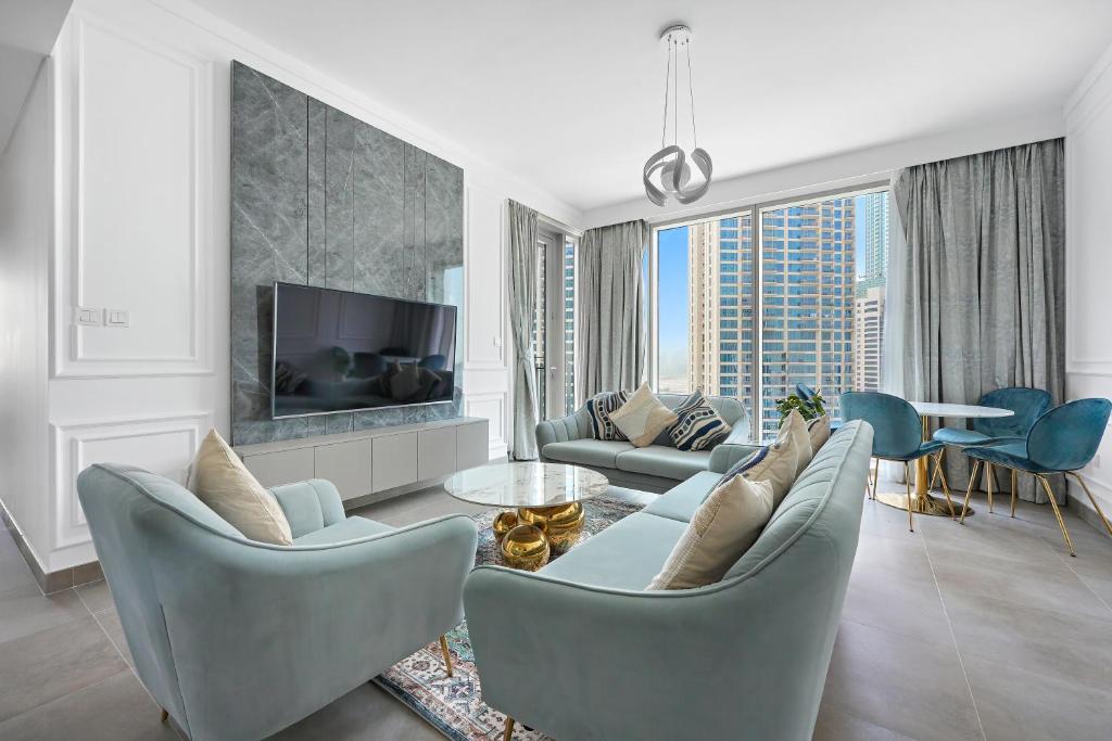 ein Wohnzimmer mit blauen Stühlen und einem TV in der Unterkunft WelHome - Stunning Apartment With Sea Views in Creek Harbour in Dubai