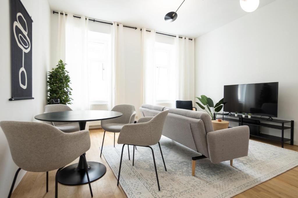sala de estar con mesa, sillas y TV en Modern apartment in a top location of Vienna en Viena