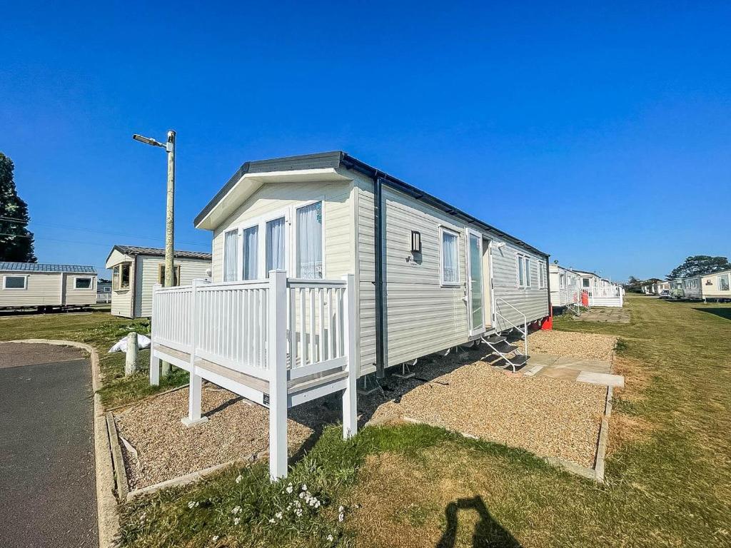 una fila de casas móviles estacionadas en un campo en Modern 8 Berth Caravan With Decking At Valley Farm, Essex Ref 46575v en Great Clacton