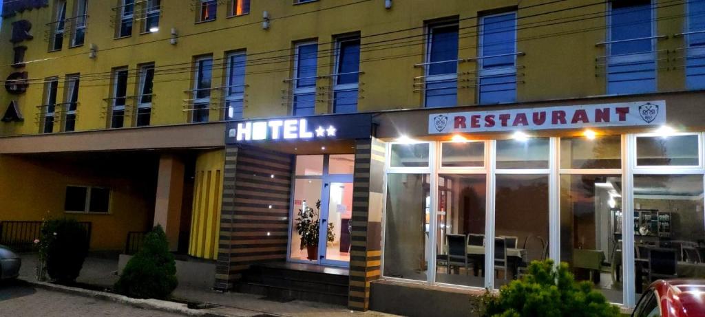 un edificio amarillo con un restaurante delante de él en Hotel Riga, en Arad