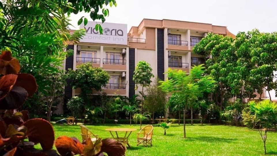 a hotel building with a table and chairs in a yard at VICTORIA COMFORT INN in Kisumu