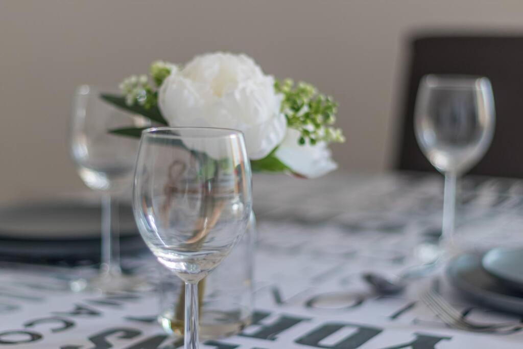 una mesa con tres copas de vino y una flor blanca en Station 14 - Vacation Home, en Gelligaer