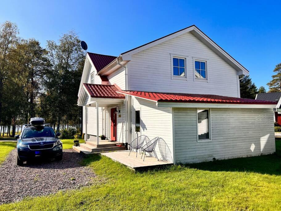 een wit huis met een auto ervoor geparkeerd bij Riverfront Cosy Villa in Luleå in Luleå