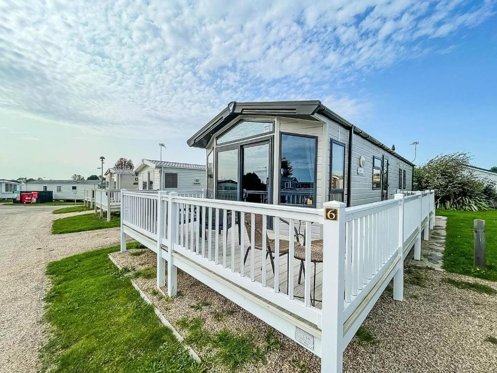 a house with a white fence and a porch at Wonderful 6 Berth Caravan For Hire By A Stunning Norfolk Beach Ref 19006sd in Scratby