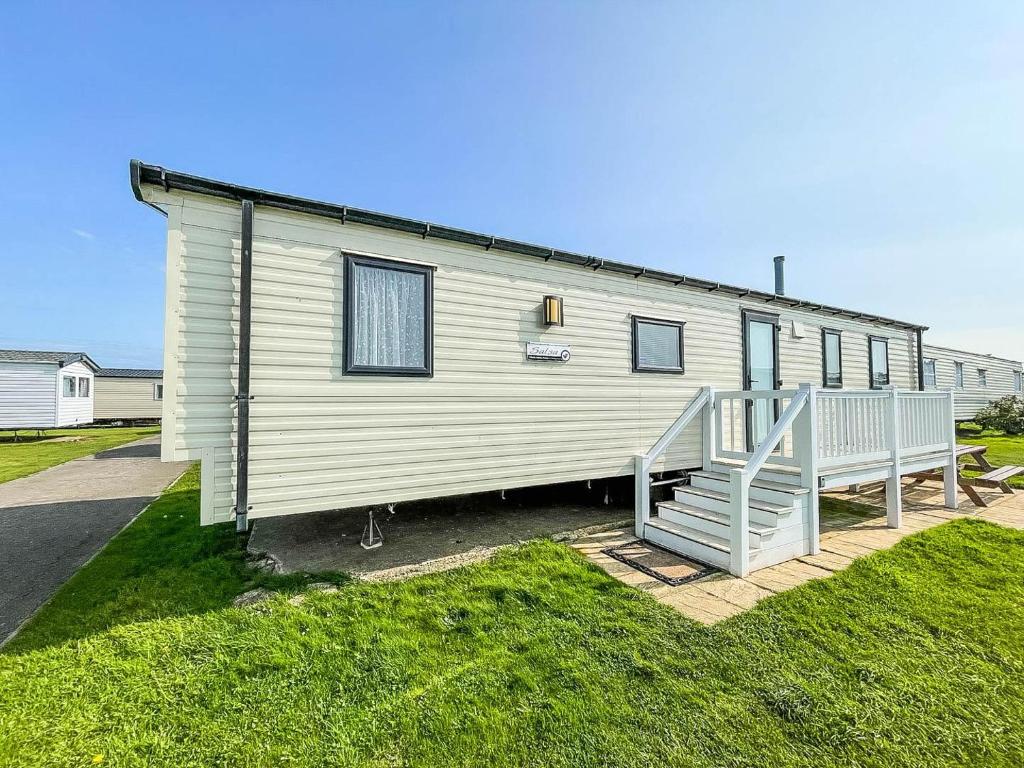 a white house with a porch and a staircase at 8 Berth Caravan With Decking At Caister Beach In Norfolk Ref 30016s in Great Yarmouth