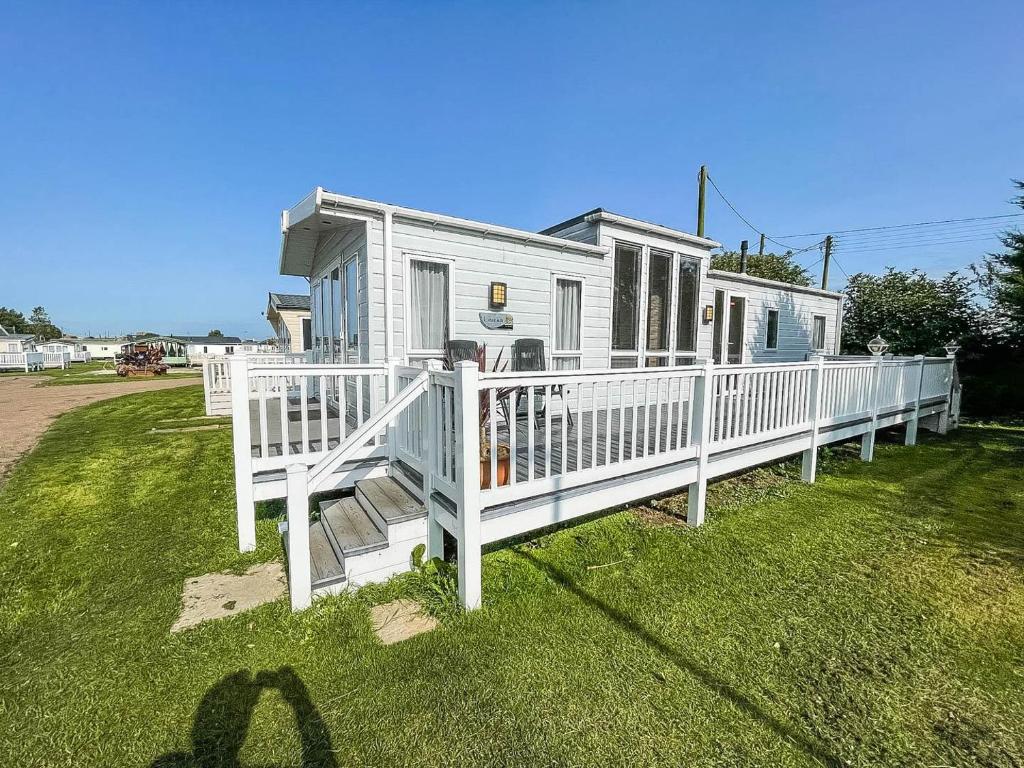 een huis met een witte veranda en een witte leuning bij Luxury Caravan With Decking Nearby Scratby Beach In Norfolk Ref 50001bm in Great Yarmouth