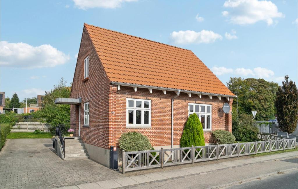 een klein rood bakstenen huis met een oranje dak bij 2 Bedroom Cozy Home In Ryomgrd in Ryomgård