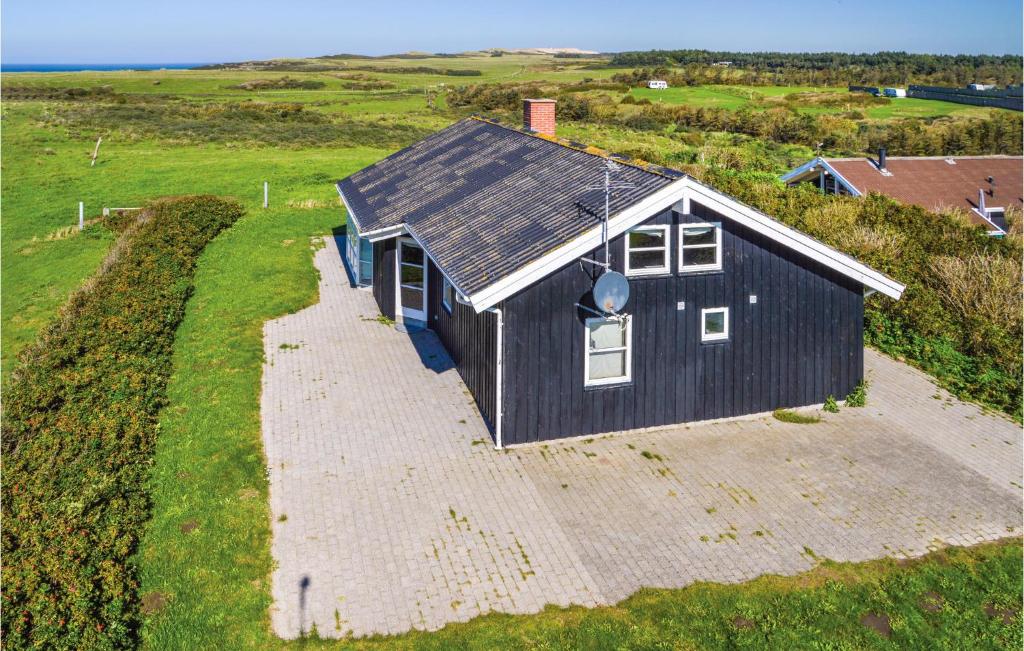 una casa negra sentada en la cima de un campo en Awesome Home In Lkken With 4 Bedrooms, Sauna And Wifi, en Lønstrup