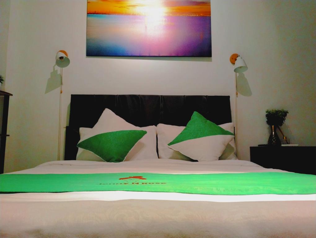 a bed with green and white pillows on it at Jenny N Rose Travellers Inn in Manila