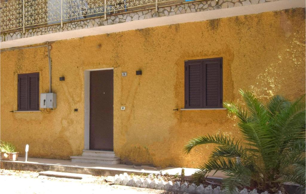 un bâtiment jaune avec deux portes et un palmier dans l'établissement Nice Apartment In Gizzeria With Kitchen, à Gizzeria