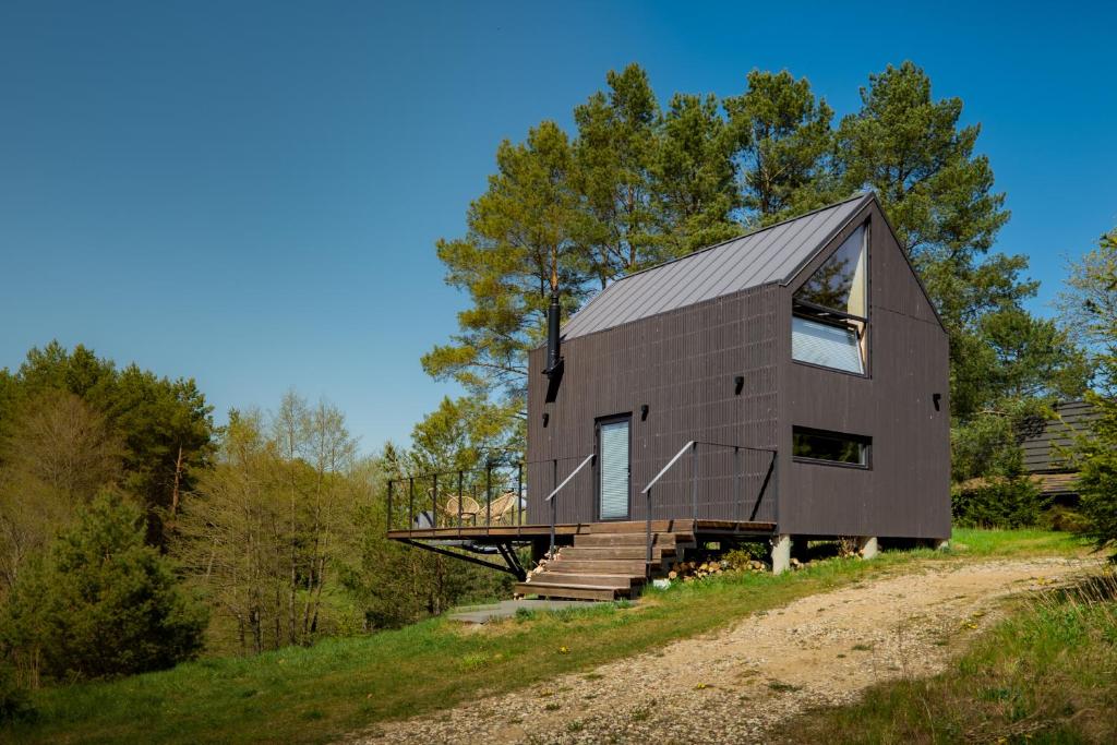 a timber clad house on a hill with a dirt road at Dom na Kaszubach Lektura in Fingrowa Huta