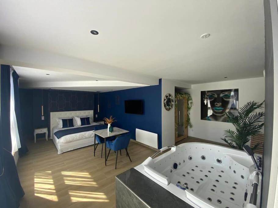 ein Badezimmer mit einer Badewanne und ein Schlafzimmer mit einem Bett in der Unterkunft La Suite Saphir – spa privatif in Nancy