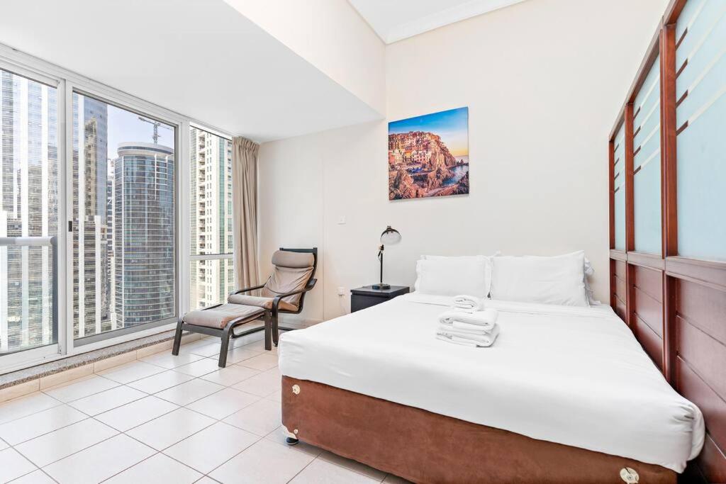 - une chambre avec un lit, une chaise et des fenêtres dans l'établissement StoneTree - Studio with Amazing View in JLT, à Dubaï