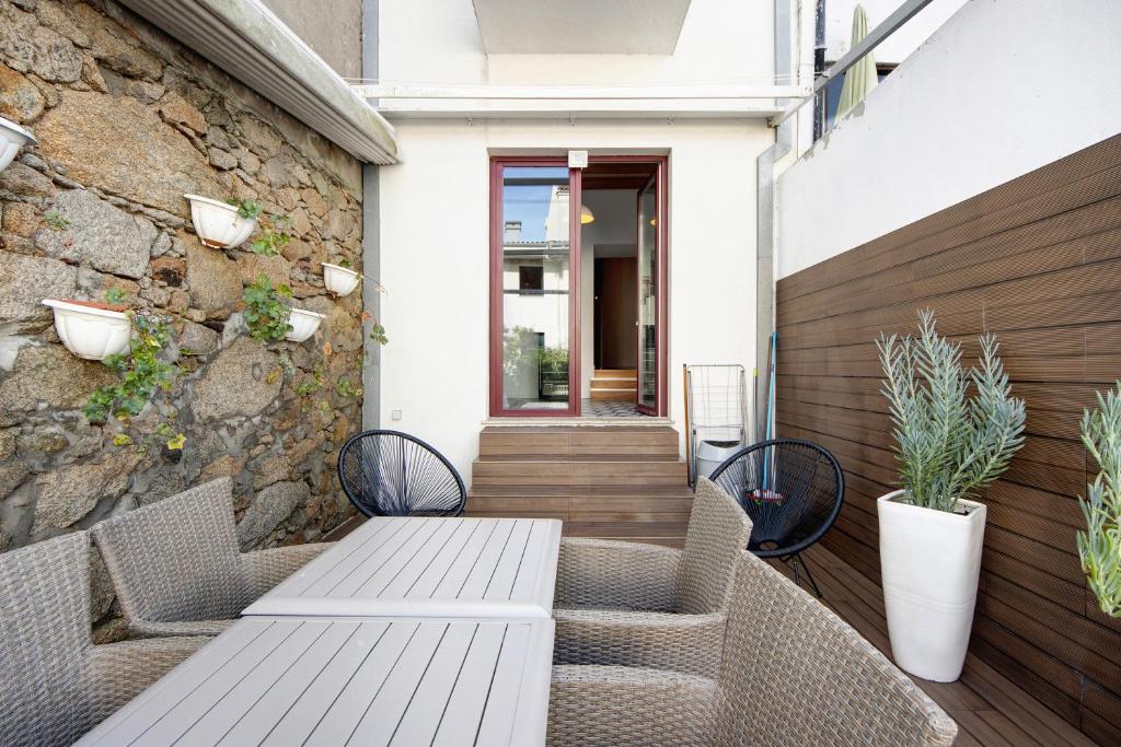 un patio con mesa, sillas y pared de piedra. en Lidador House Vila do Conde en Vila do Conde