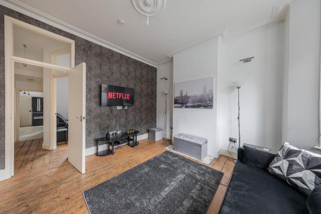 ein Wohnzimmer mit einem Sofa und einem TV an der Wand in der Unterkunft Charming 1 Bed Flat w Courtyard in Central London in London