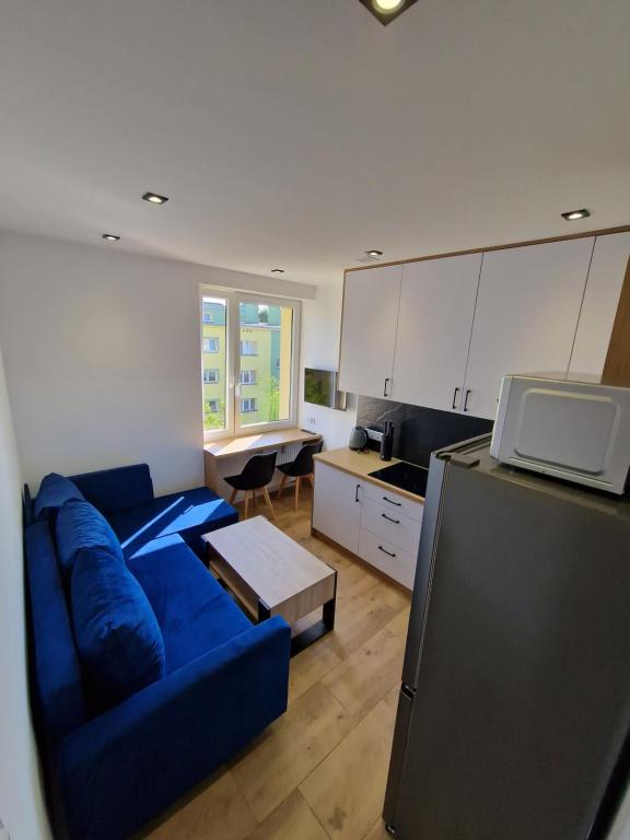 ein Wohnzimmer mit einem blauen Sofa und einer Küche in der Unterkunft YourSecondFlat Sobieski Apartment in Dębica