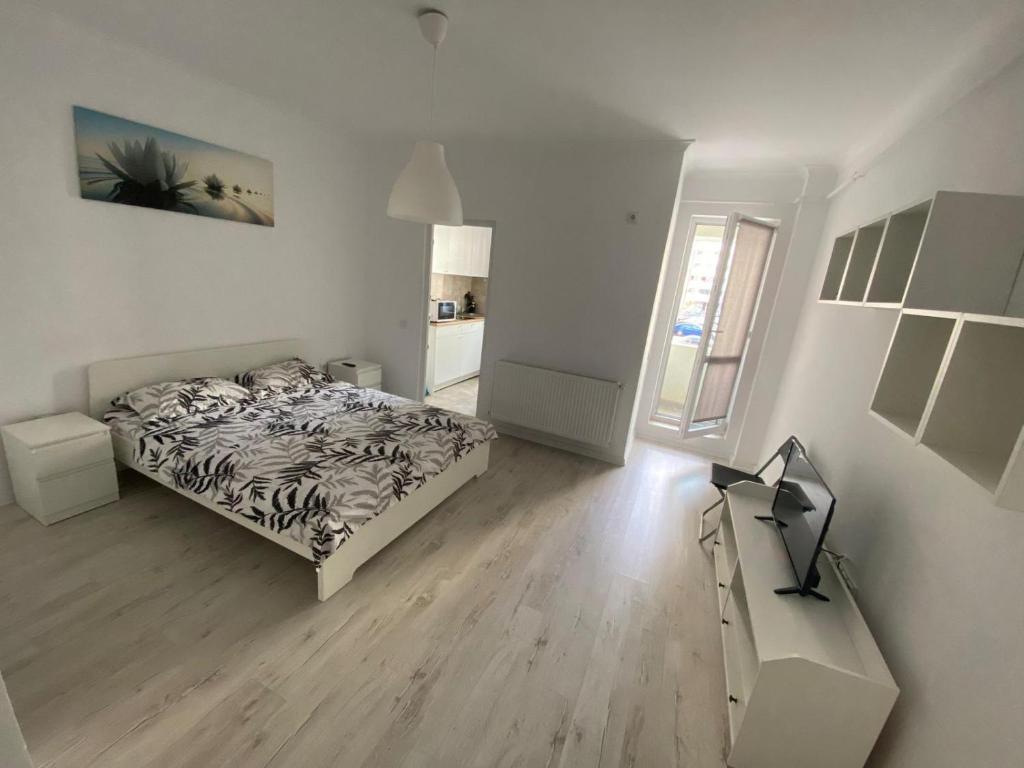 a white bedroom with a bed and a desk at Relax Studio Militari Residence Sector 6 in Roşu
