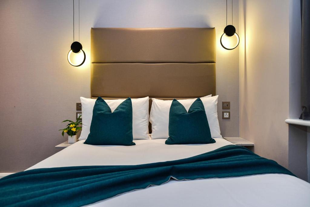 a bedroom with a bed with green and white pillows at Queens Park Premier London Hyde Park in London