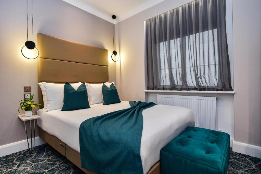 a hotel room with a large bed and a window at Queens Park Premier London Hyde Park in London