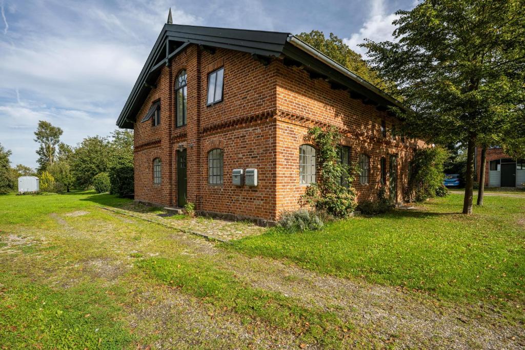 a brick building with a black roof on a field at Wohnung 1 Terrassenwohnung in Stockelsdorf
