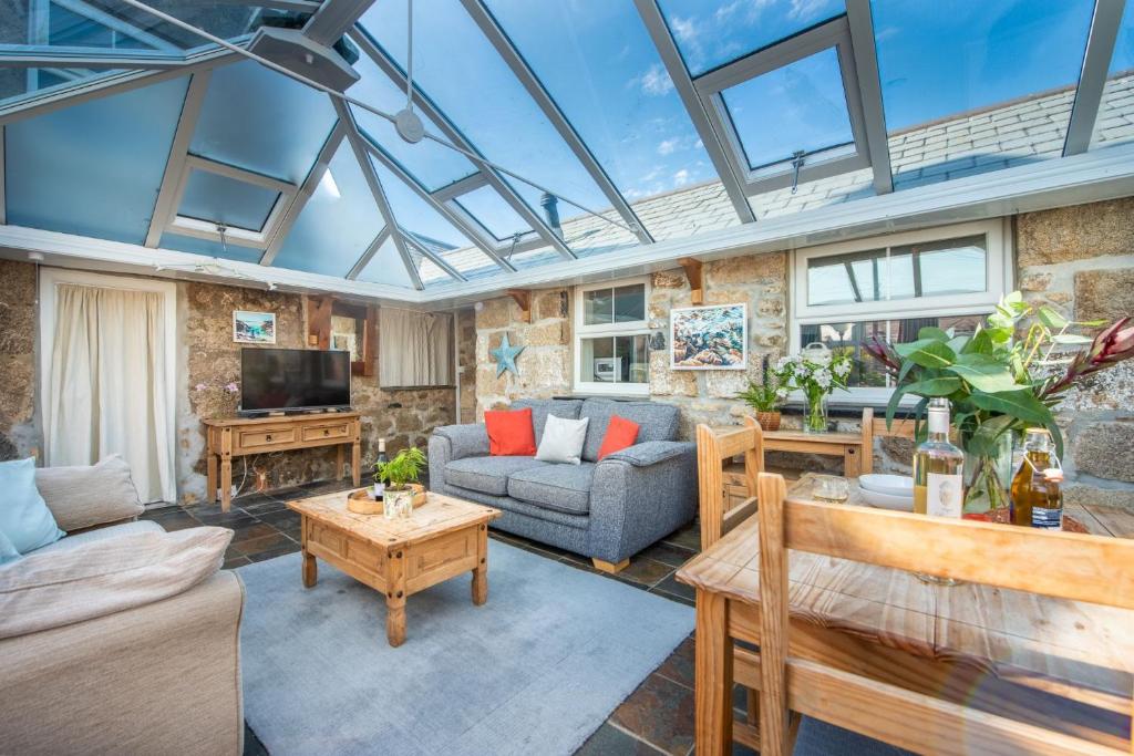 a living room with a glass ceiling with a couch and a table at Laity Vean Hideaway in Carbis Bay