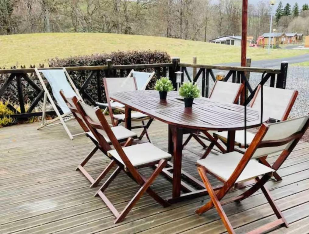 a wooden table and chairs on a deck at Chalet 77 proche S Besse in Égliseneuve-dʼEntraigues