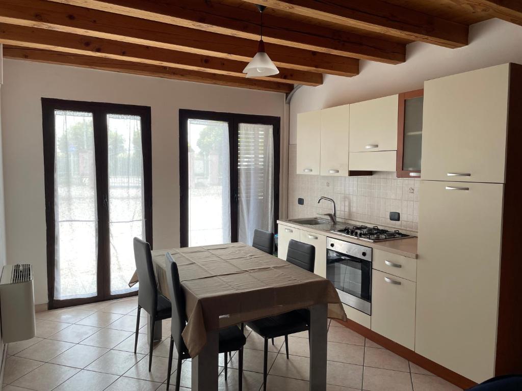 a kitchen with a table and chairs and some windows at Appartamento in corte in Bagnolo