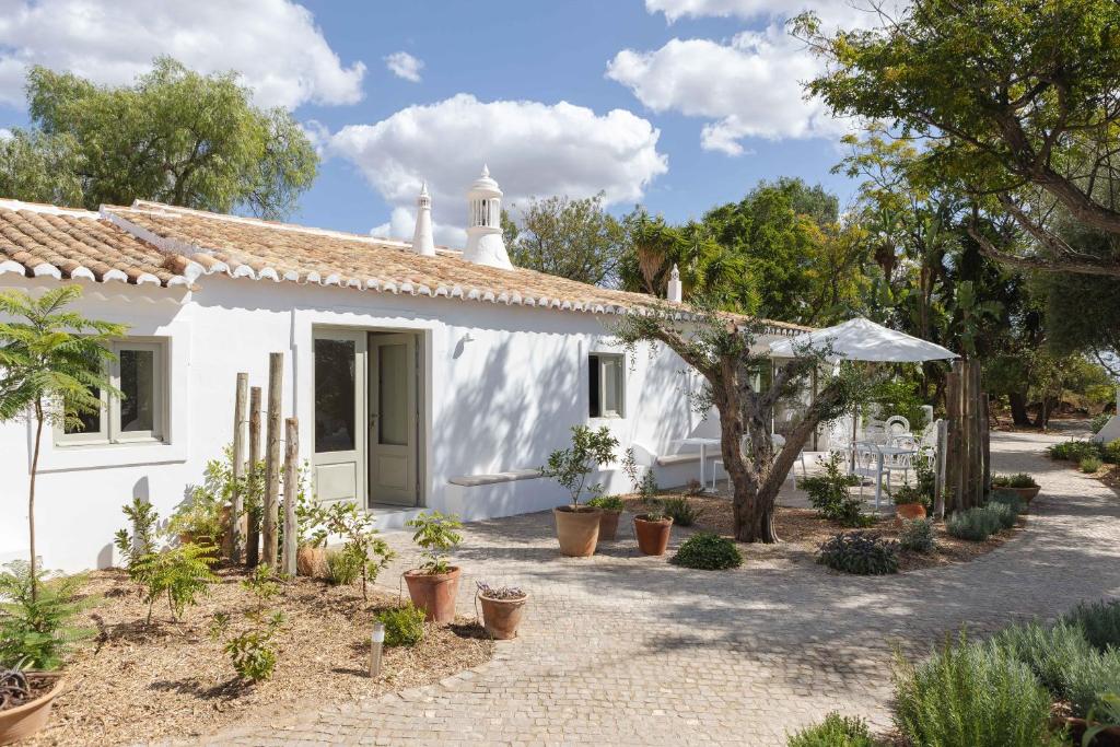 una casa blanca con plantas delante en Âmago Guesthouse en Santa Bárbara de Nexe