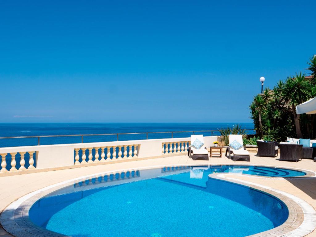 a swimming pool with the ocean in the background at Villa Palma - Sunset Sea Views with Pool, Jacuzzi, Sauna and Games Room in Mellieħa