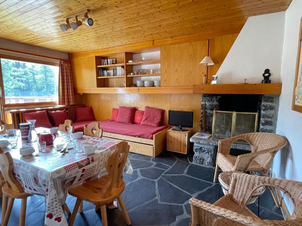 a living room with a table and a red couch at Appartement proche des pistes avec terrasse sud - FR-1-411-687 in Les Allues
