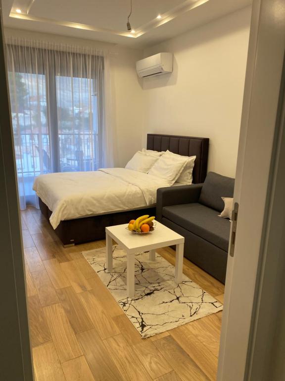 ein Schlafzimmer mit einem Bett, einem Sofa und einem Tisch in der Unterkunft Apartman PORTO in Trebinje