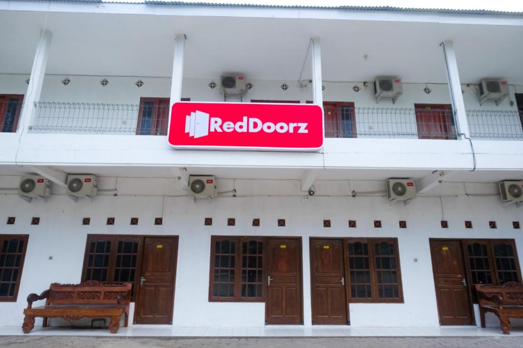 a red door sign on the side of a building at RedDoorz near Plaza Ambarrukmo Yogyakarta in Seturan