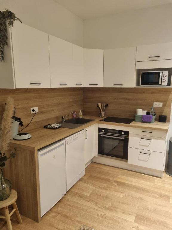a kitchen with white cabinets and a wooden counter top at Chez Clement et Mathilde - T2 hyper centre tout équipé in Saint-Amand-les-Eaux