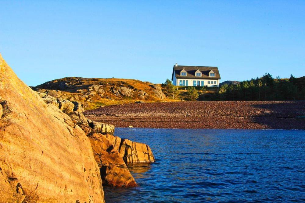 a house on a hill next to a body of water at Shore Croft in Aultbea