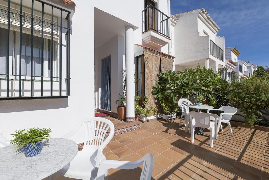 a patio with white chairs and tables on a building at Casa Ocon in Conil de la Frontera